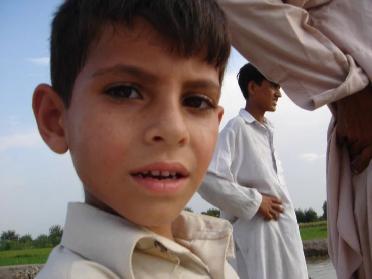 a small boy with his face half open stands next to a man
