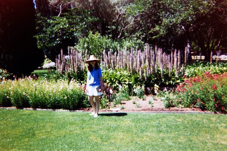 a woman in a hat stands on the grass