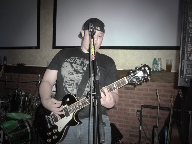 a man standing next to a microphone while playing a guitar