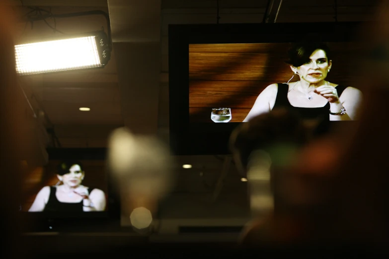 a woman with a cell phone standing in front of a television