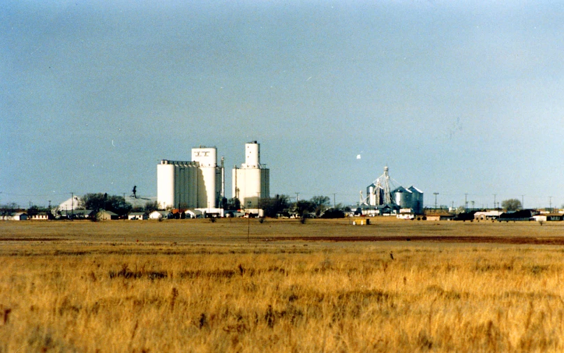 a grain farm with three silos behind it