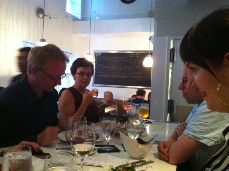 three adults drinking wine and sitting at the bar