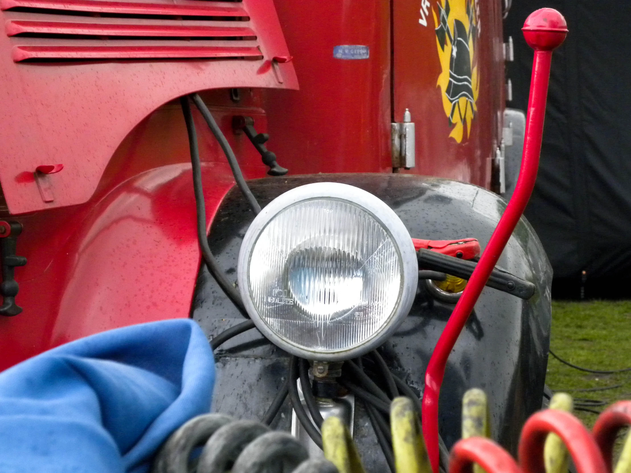 the headlight of a red truck parked on top of a field