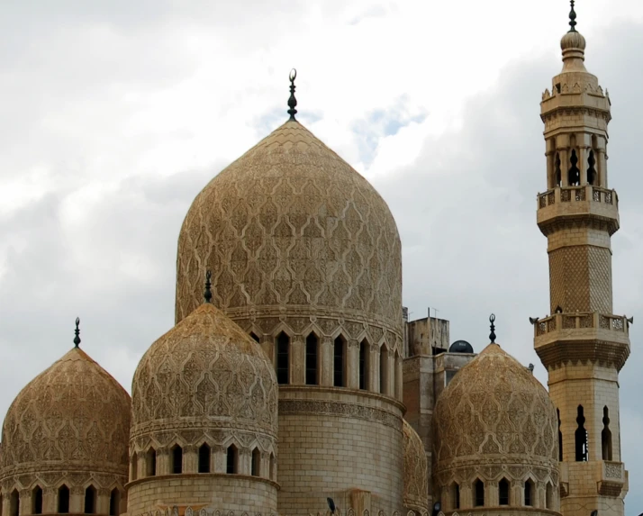 a mosque with two towers standing in front of a cloudy sky