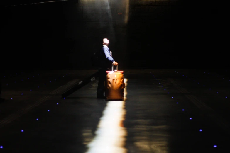 a man standing in front of a black background with his suitcase