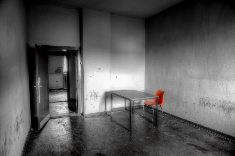 an orange chair sits alone in a room with white walls