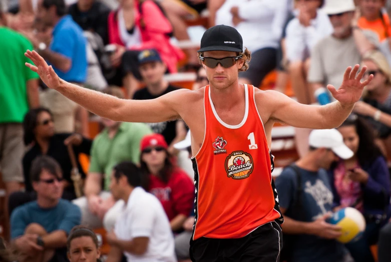 a man in an orange shirt and black shorts holding his arms out with the other hand