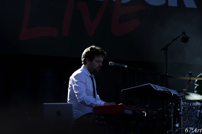 man playing electronic keyboard in front of microphone