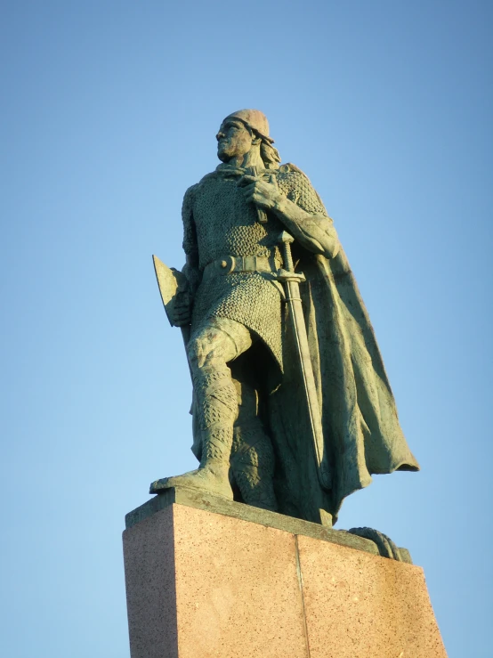 a statue of a medieval soldier holding a sword in one hand and two hands in the other