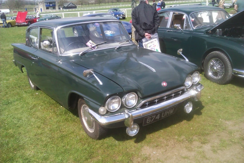 two older cars parked next to each other on a field