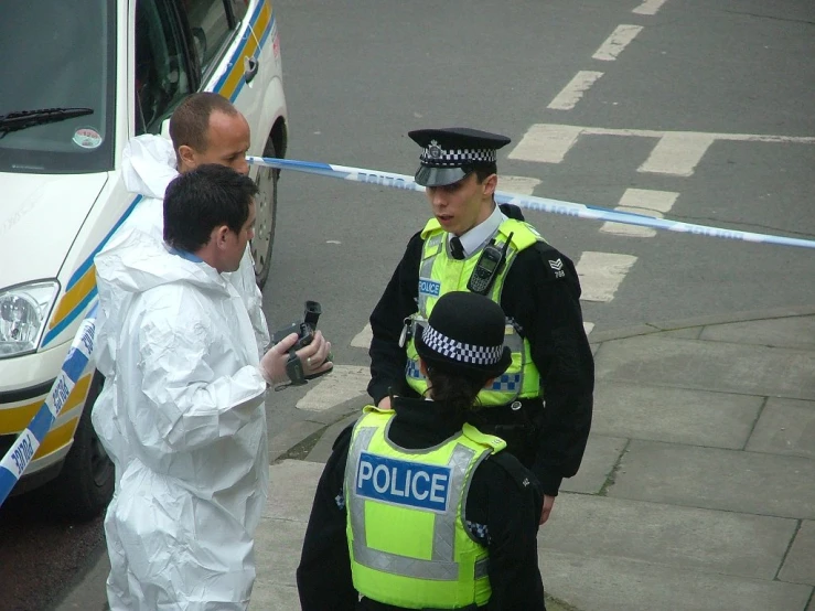 two police officers talking to an officer in protective clothing