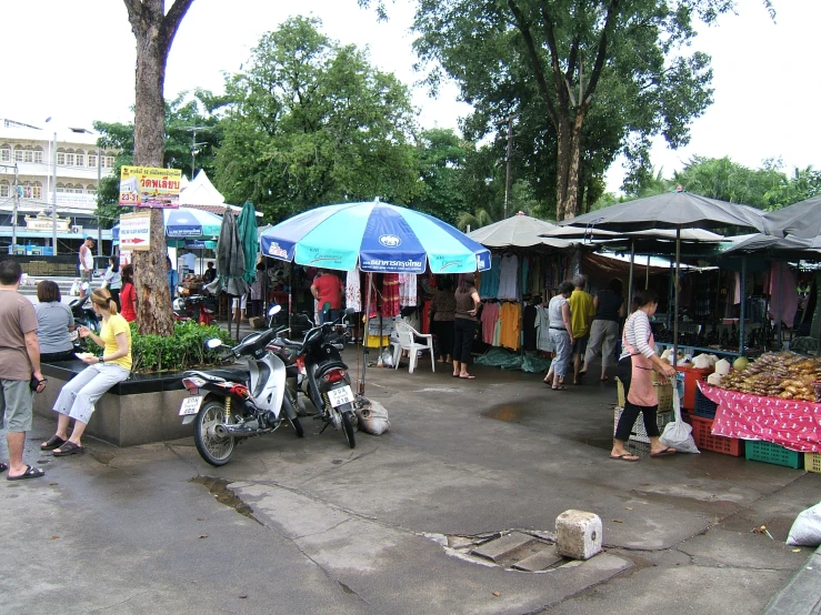 a market area with several people at stalls on the side walk