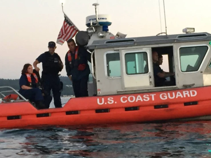 people in a u s coast guard boat near a flag