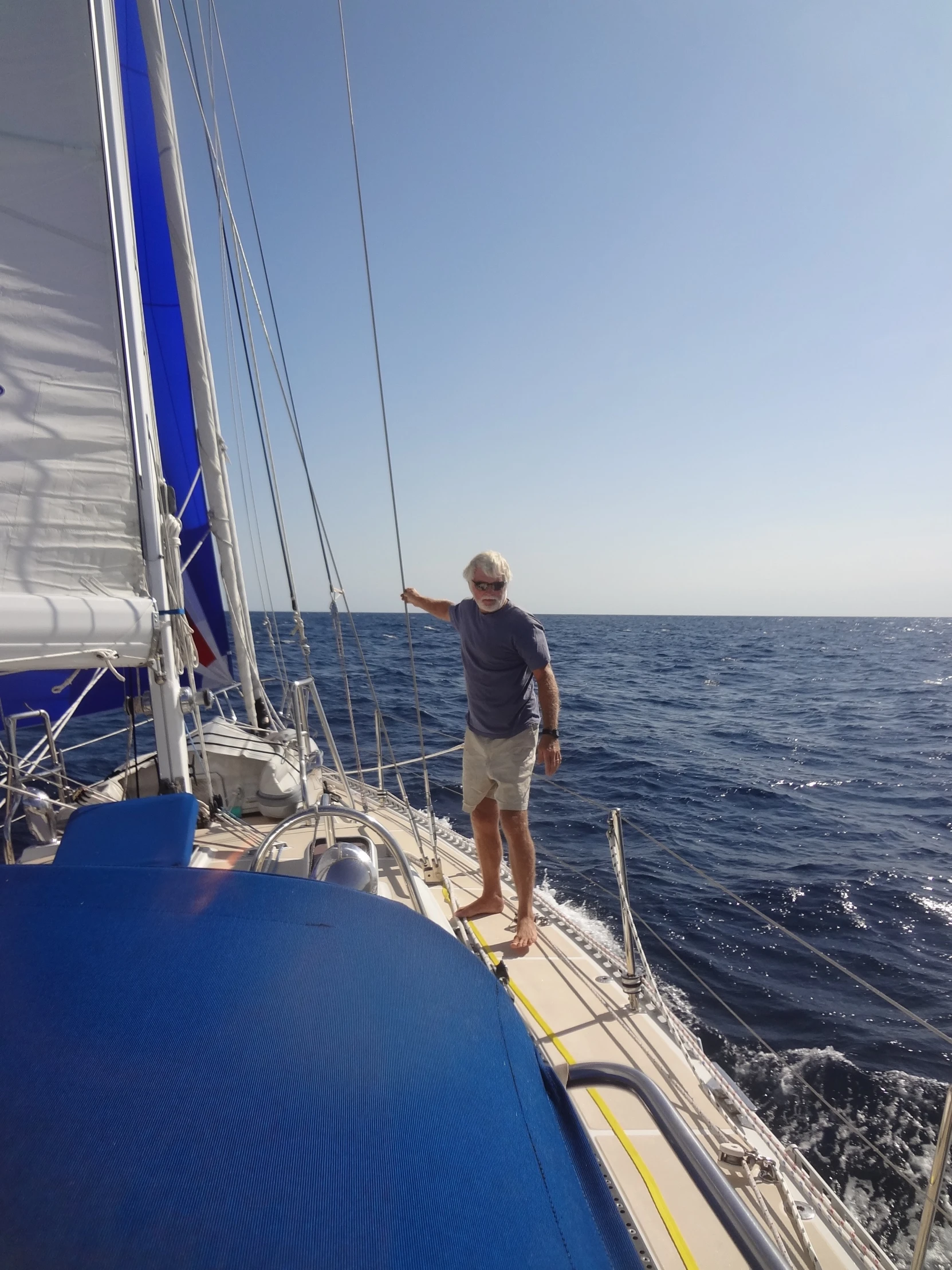 a man stands on the deck of a sail boat