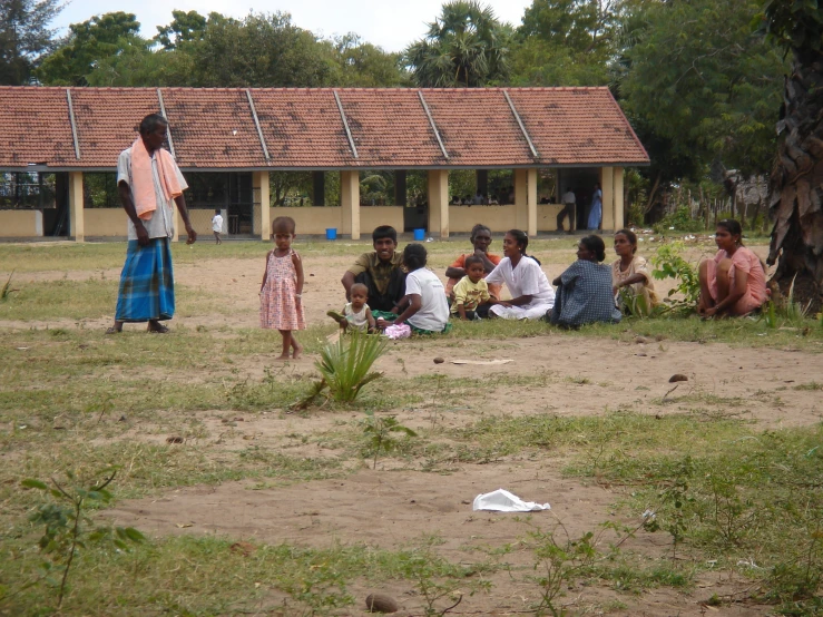 group of people sitting next to each other in a yard