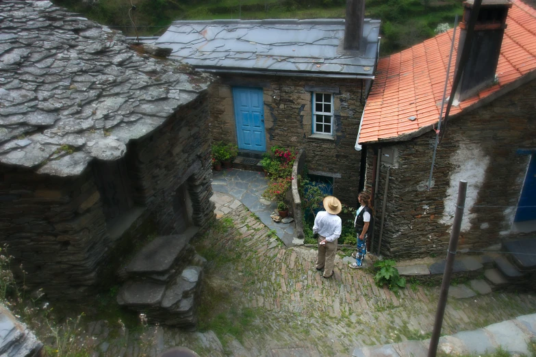 two people stand outside an old fashioned stone house