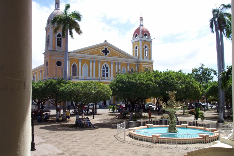 an old colonial style church with an ornate fountain in the courtyard