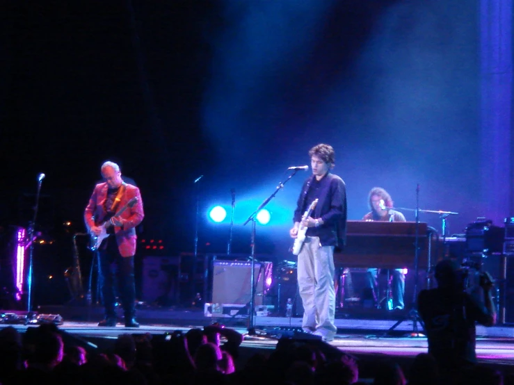 group of men standing on stage with their guitars