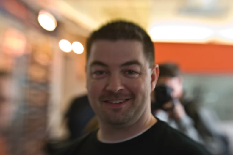 a man smiling and taking a selfie at an event