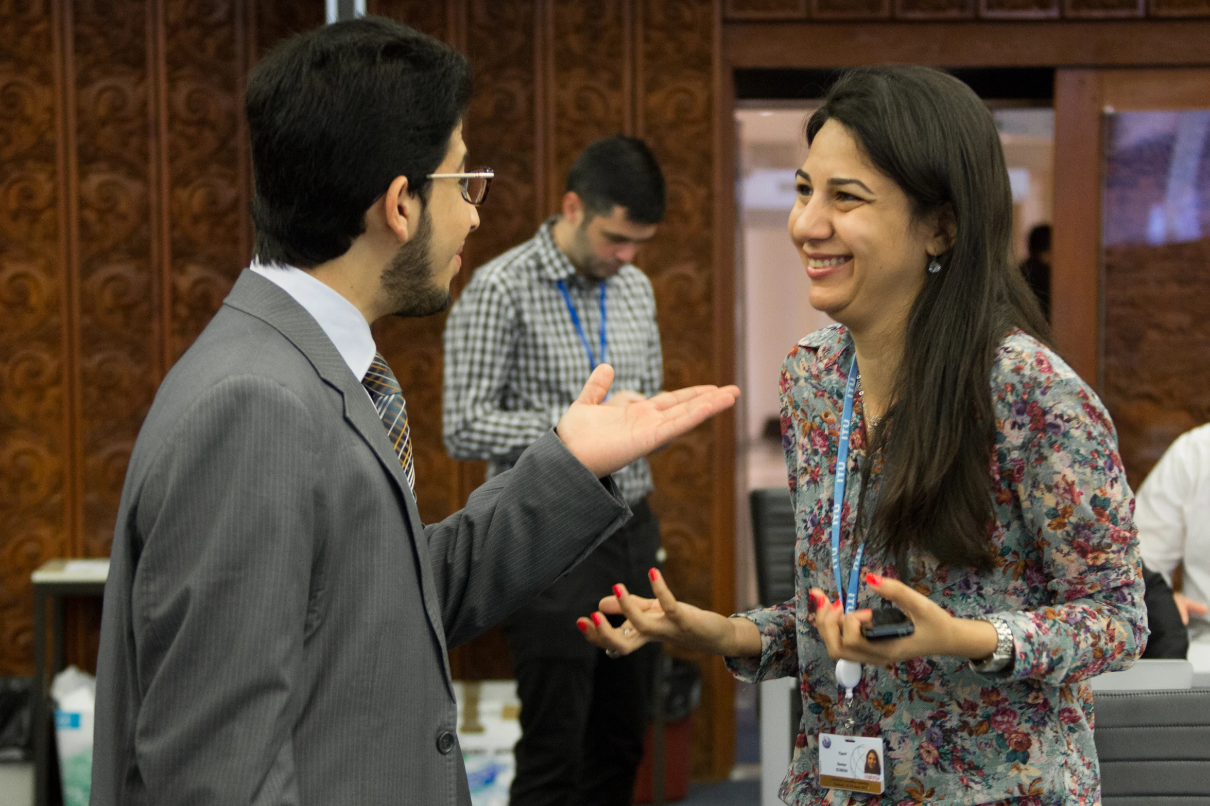 two people talking at a conference in front of wooden walls