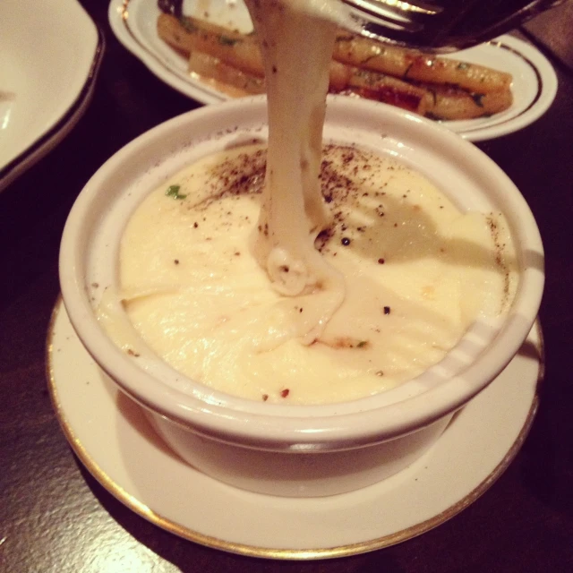 a plate is holding a white bowl with some food