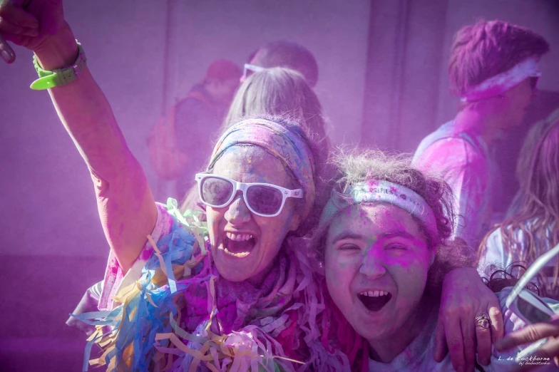 two women at a party are covered in colored powder