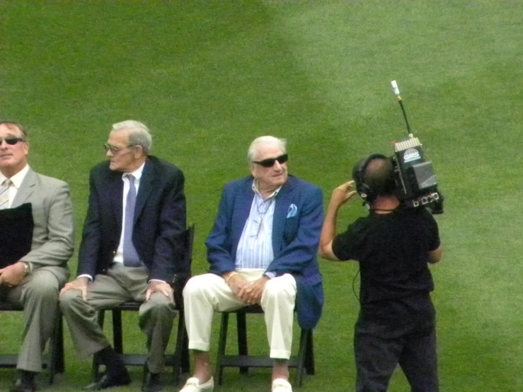 three men and a child sitting on lawn chairs