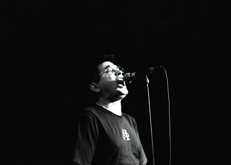 man singing into microphone in front of black background