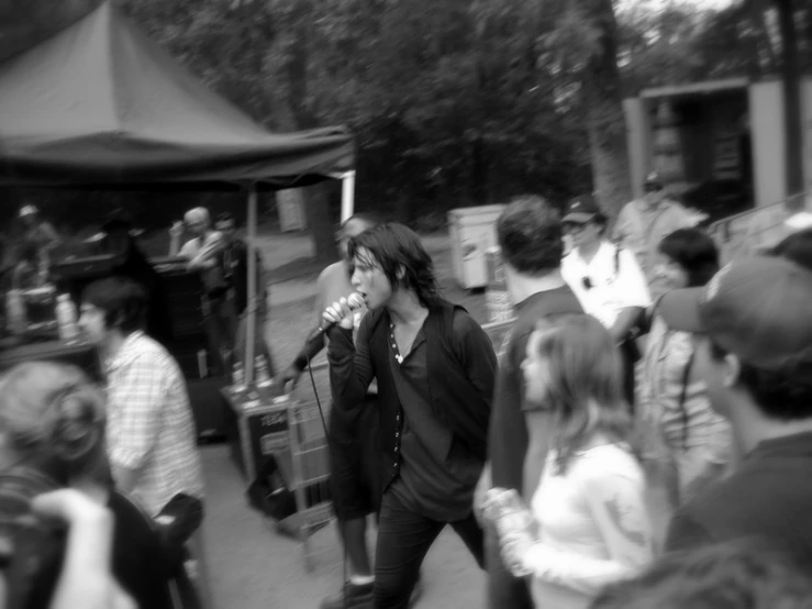 the man is walking with a microphone while listening to the band