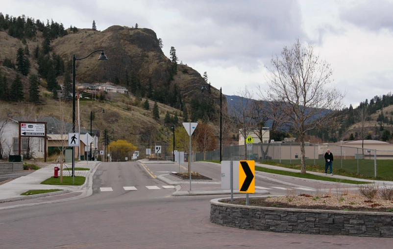 an intersection with a yellow striped sign and black and white arrow