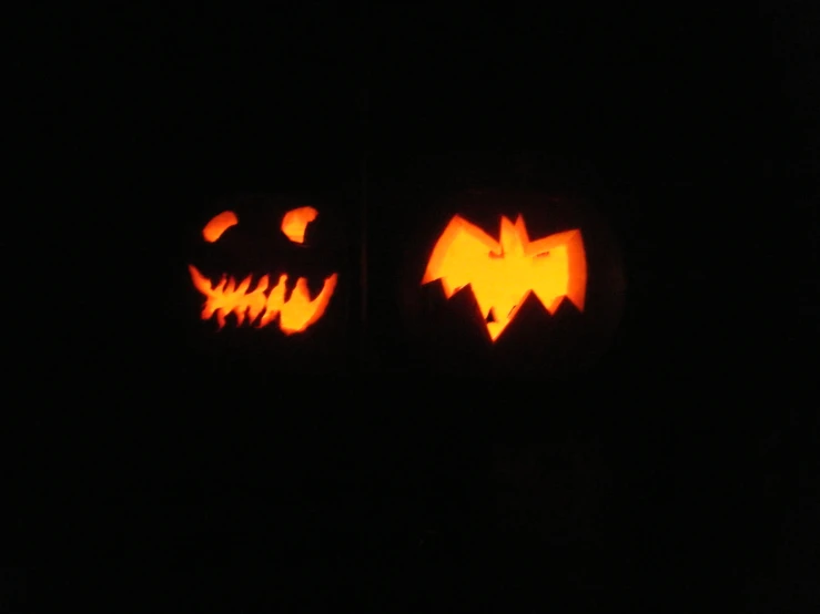 a pair of halloween pumpkins with faces carved out of them