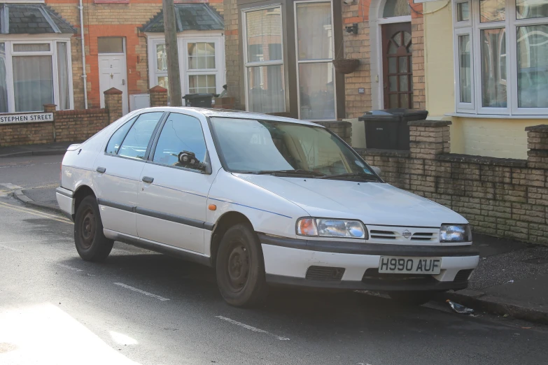 an older white car parked in front of a brick wall