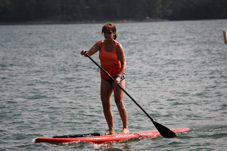 woman wearing orange and standing on a red surf board