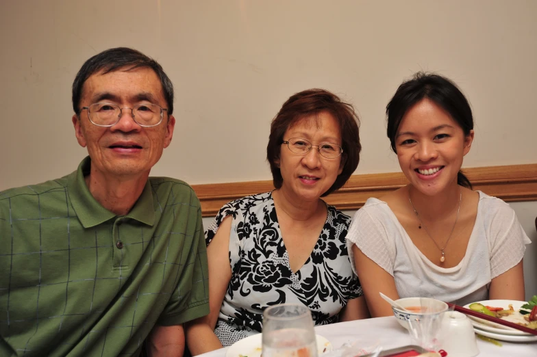 three people sitting at a table smiling for the camera