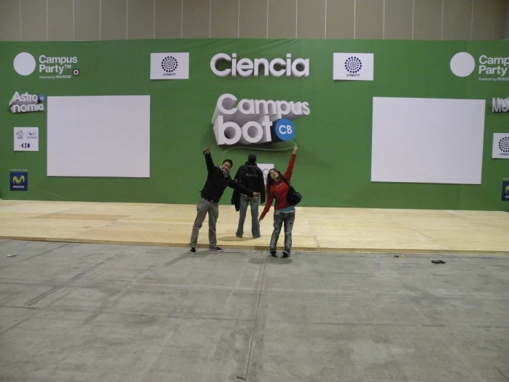 four men standing in front of a green wall holding up a large banner