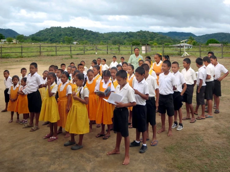 many schoolchilds and teacher lined up in uniform