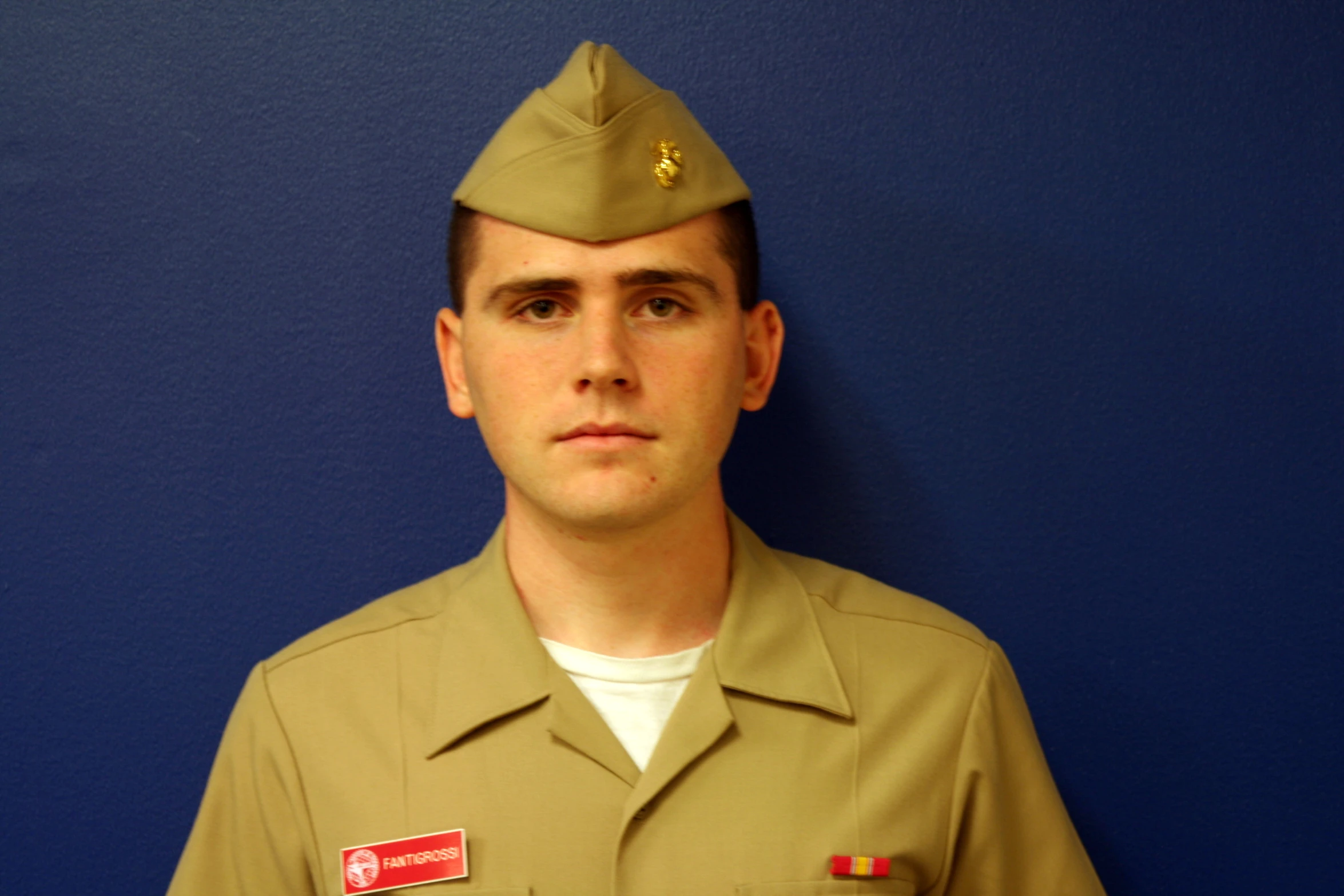 a boy in army uniform standing by a wall