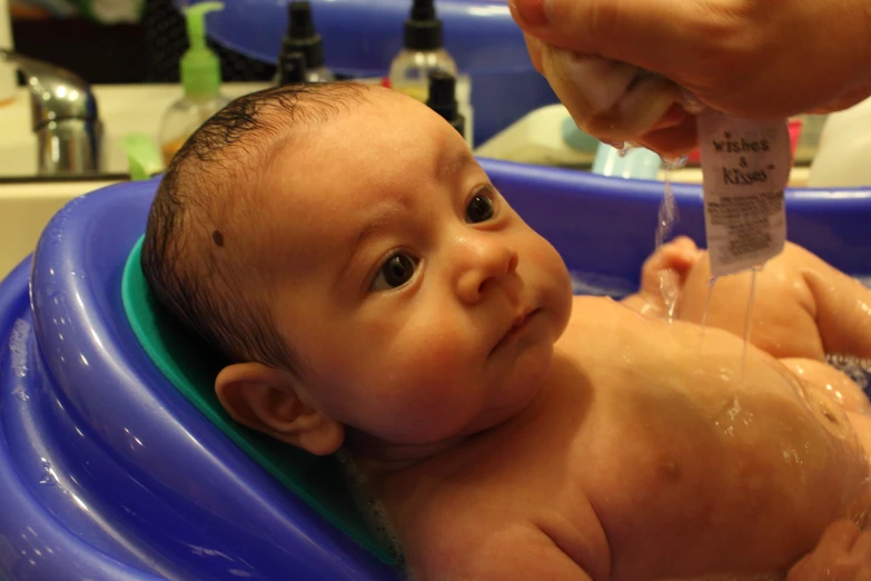 a baby taking a bath in a blue tub