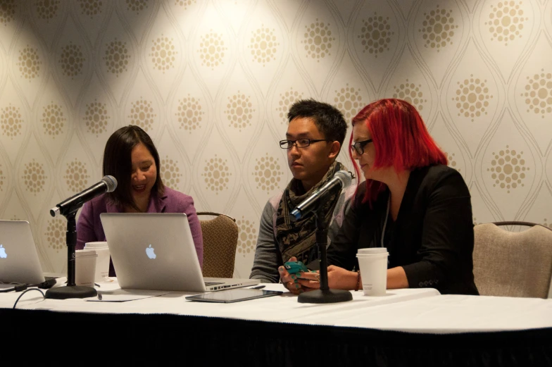 two woman are talking to an instructor while using laptops