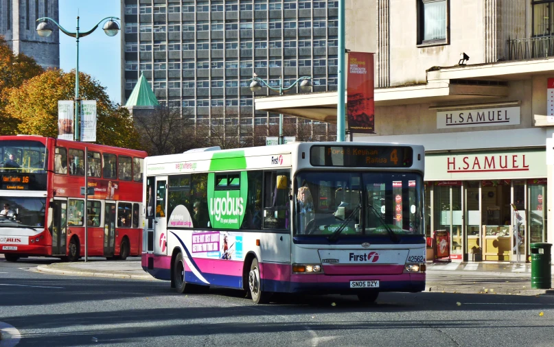 colorful bus making a turn onto the street with other buses nearby