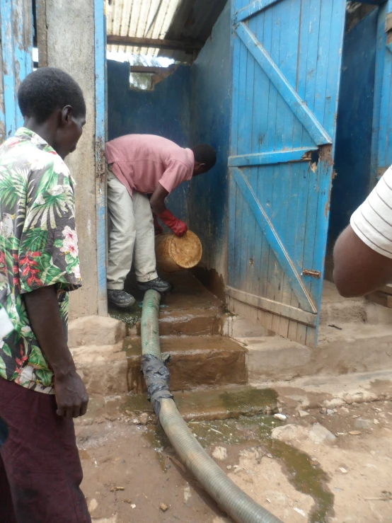 men are working on a leaking hose inside a doorway