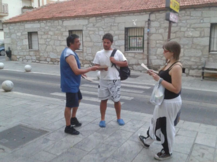 the two men are talking to a girl on the street