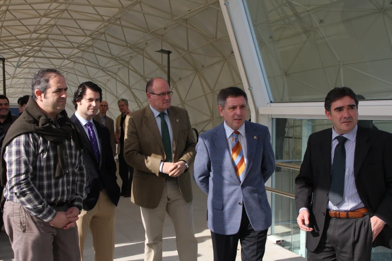 group of men in business attire standing under an umbrella