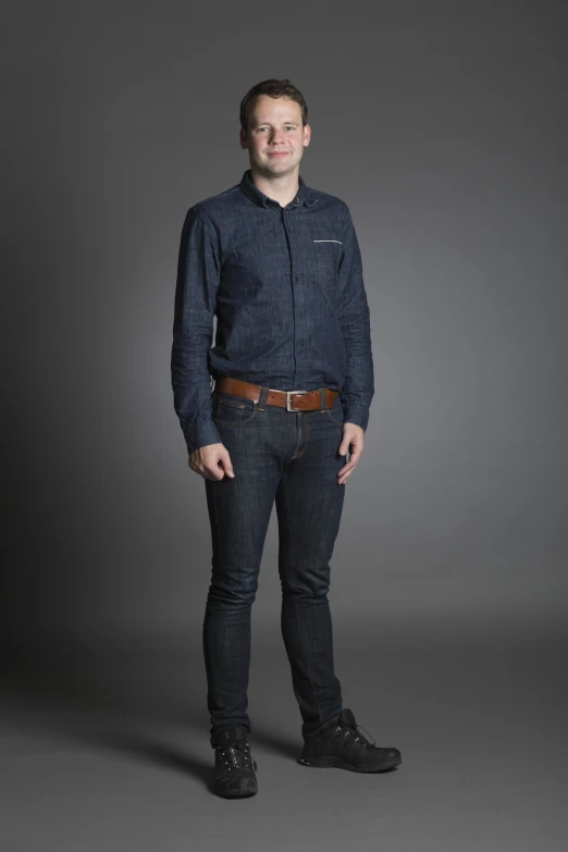 a person with a collared shirt and jeans posing for a picture