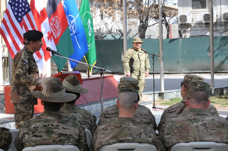 a soldier holding a microphone speaking to military personnel