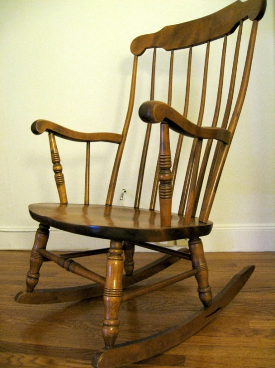 an old wooden rocking chair is shown in front of a white wall
