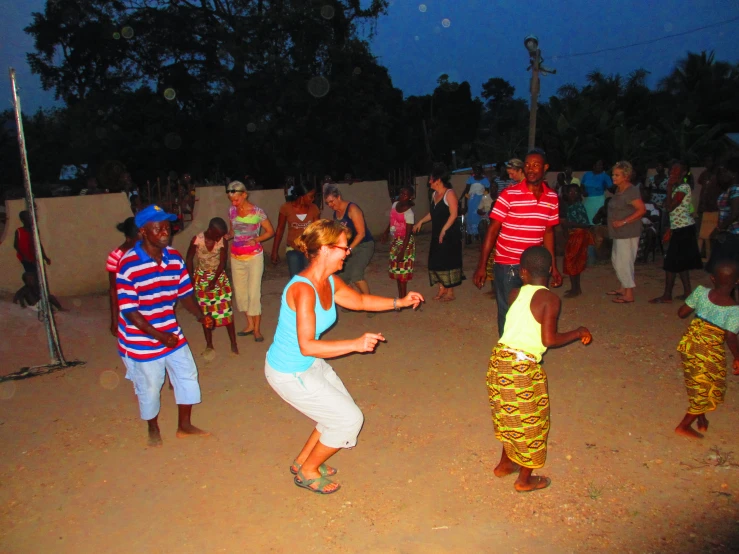 a woman in white is dancing while other people are standing on the side of the road