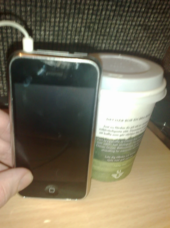 someone holding a coffee cup next to an iphone