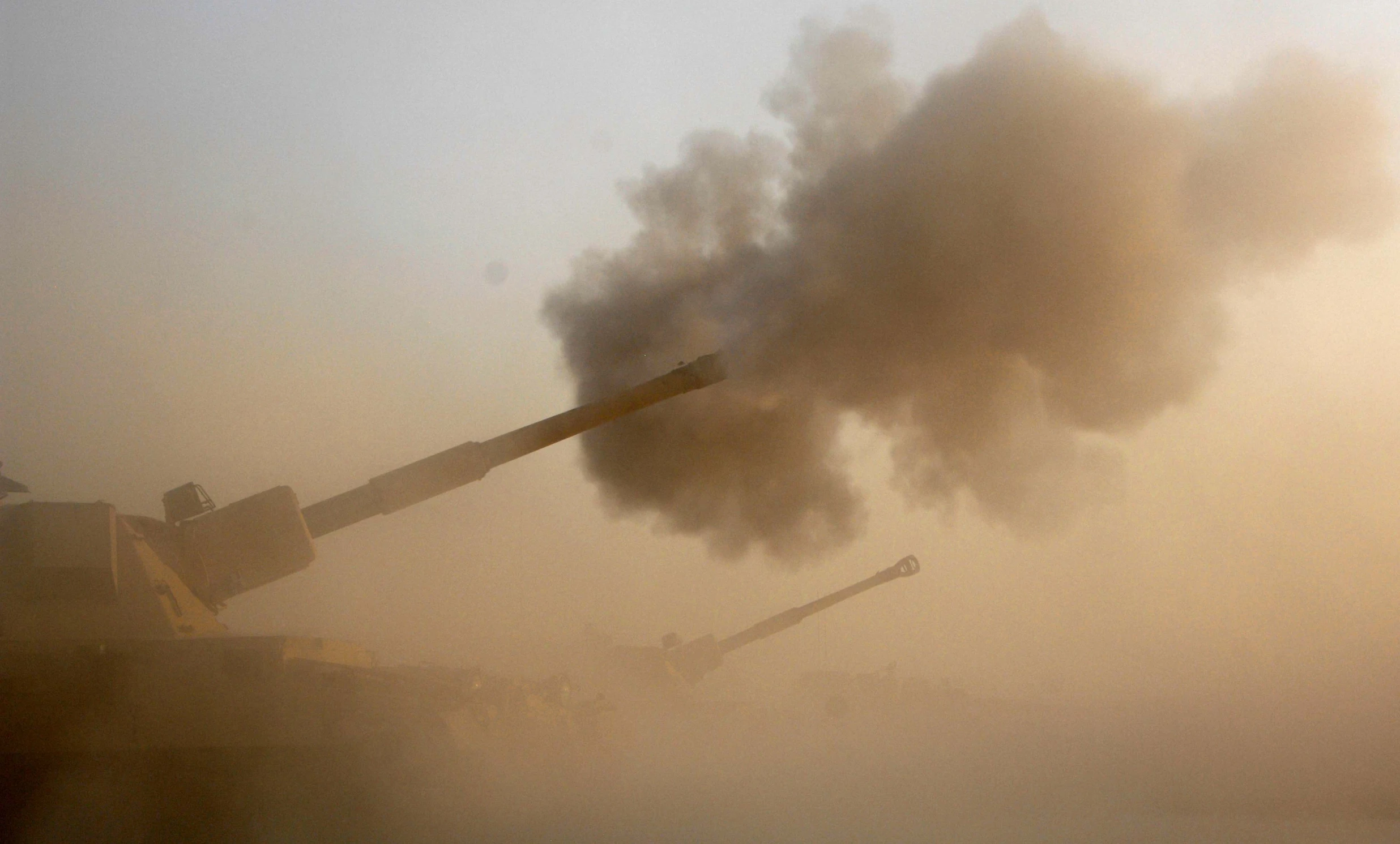 smoke billows from an army tank near buildings