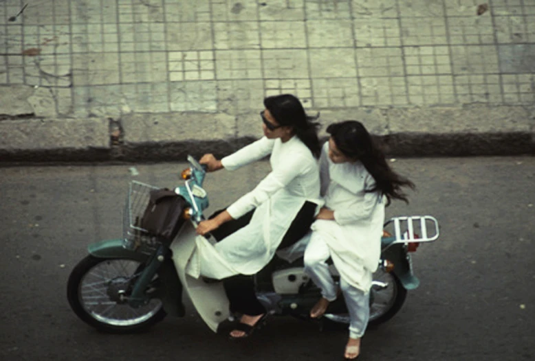 two women riding on the back of a motor cycle